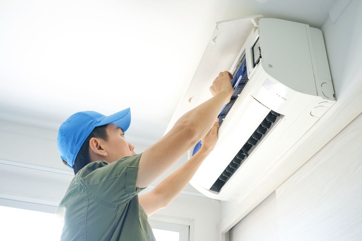 A technician works on an air conditioner indoors, highlighting HVAC mold removal services in Jacksonville, FL.